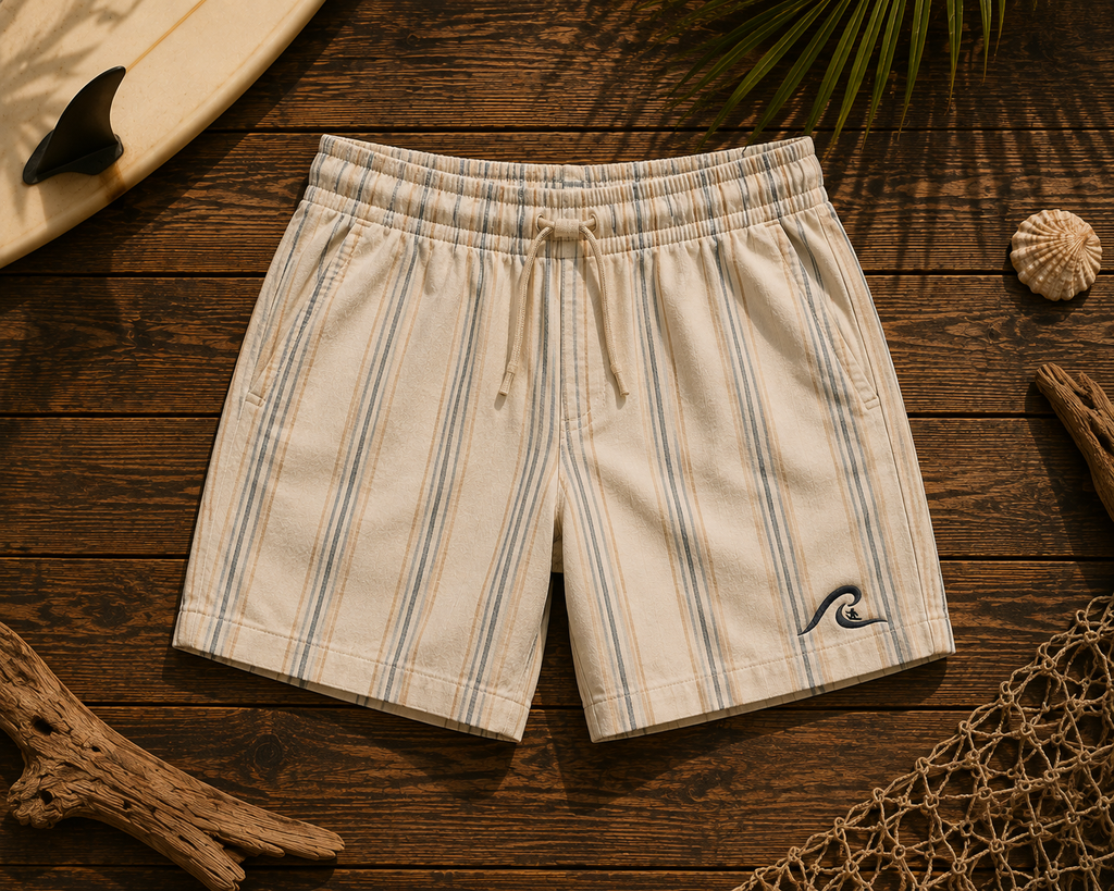Coastal Stripe Shorts flat lay on timber showing cream linen pinstripe and embroidered wave logo